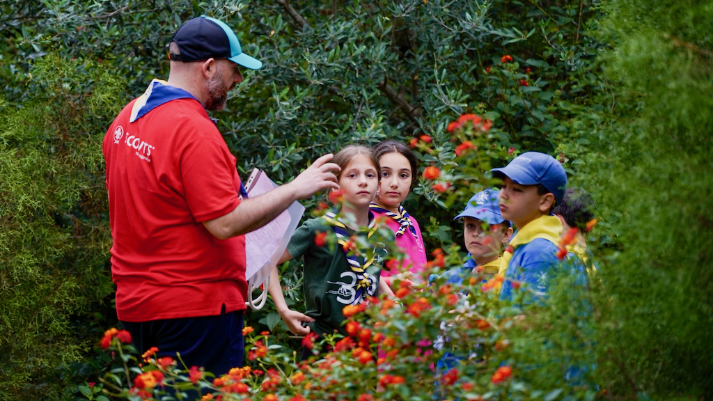 Girls listening to a leader in a wooded area
