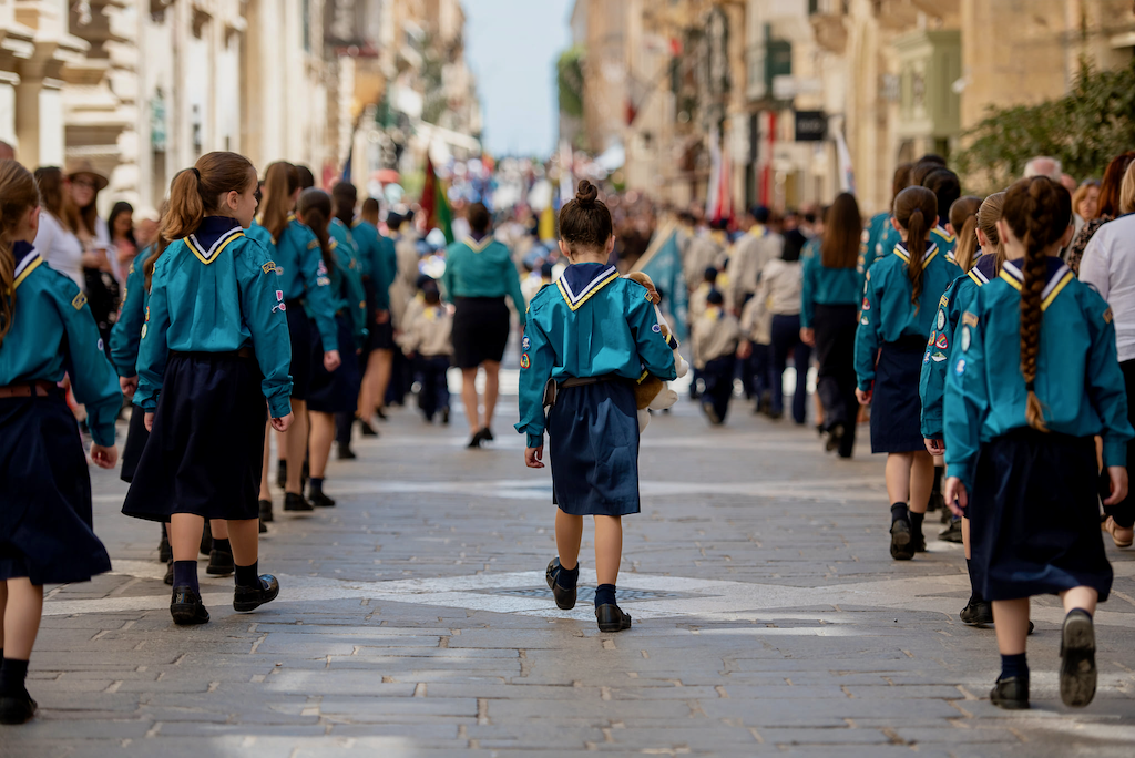 Girl Guides holding hands while marching in a parade
